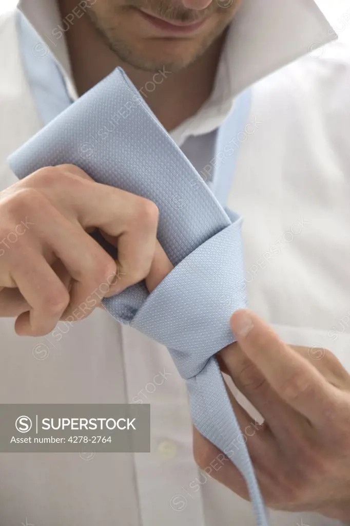 Close up  of a young man tying  a tie knot