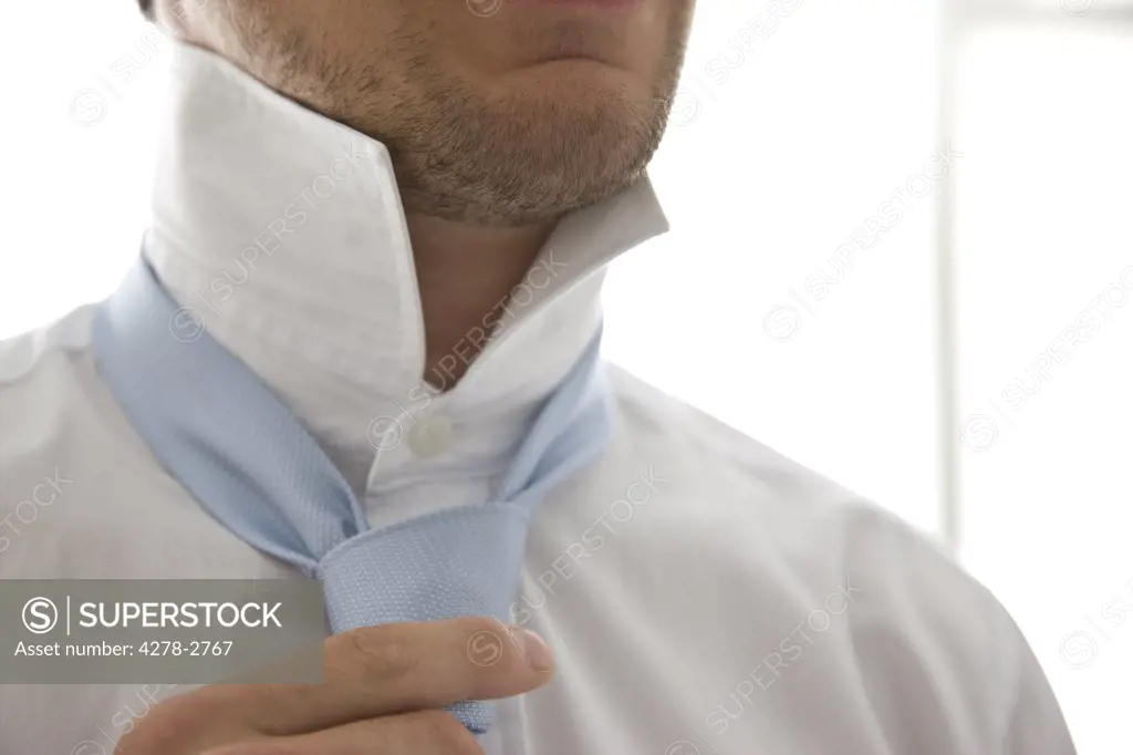 Close up  of a young man tightening his tie
