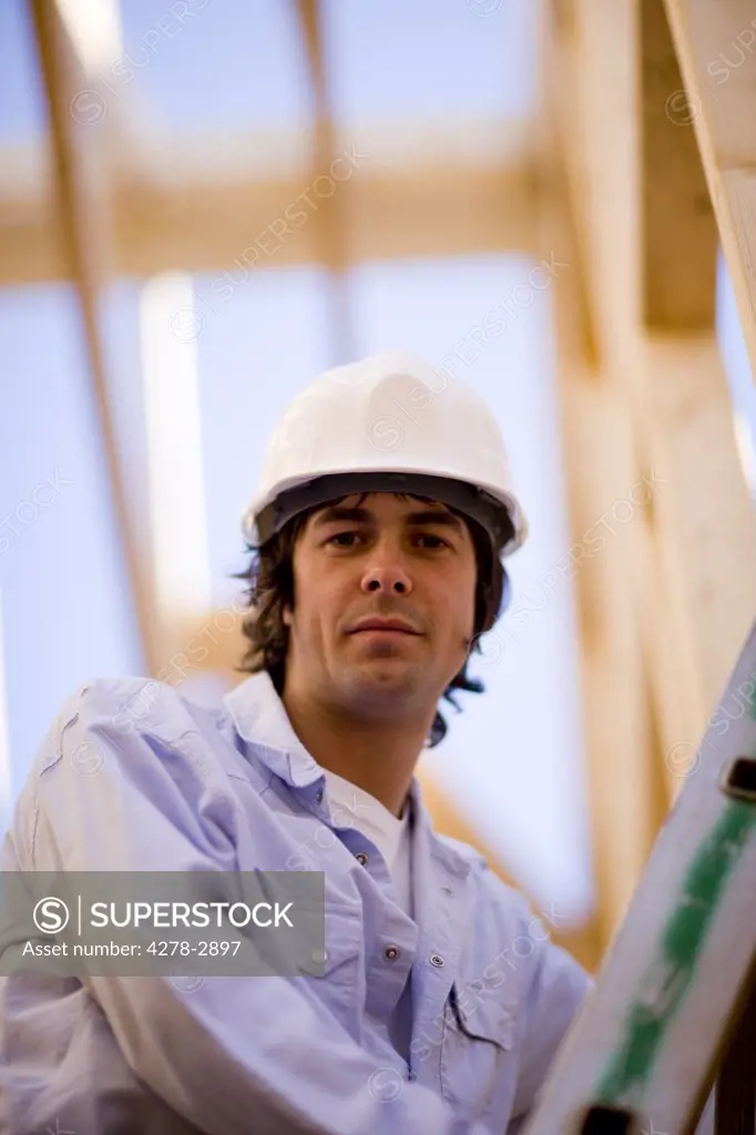 Close up of a young man climbing a ladder at construction site