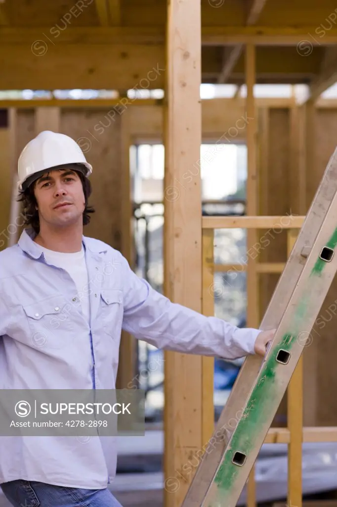 Portrait of a man climbing a ladder at construction site