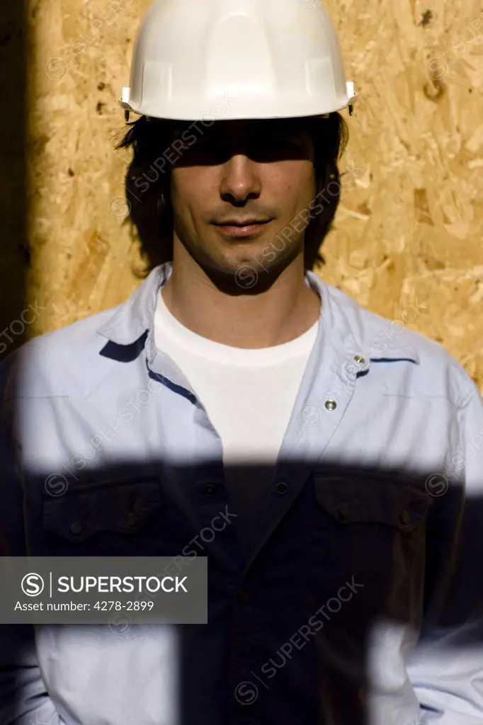 Portrait of a young man wearing hard hat at construction site with shadow
