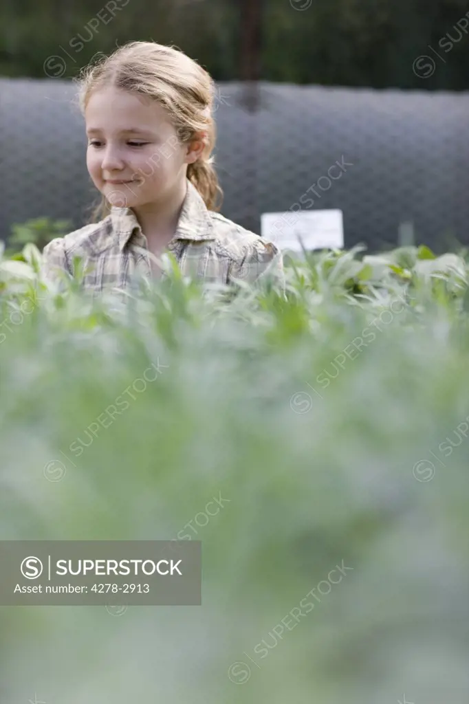 Young girl in a nursery looking at plants smiling