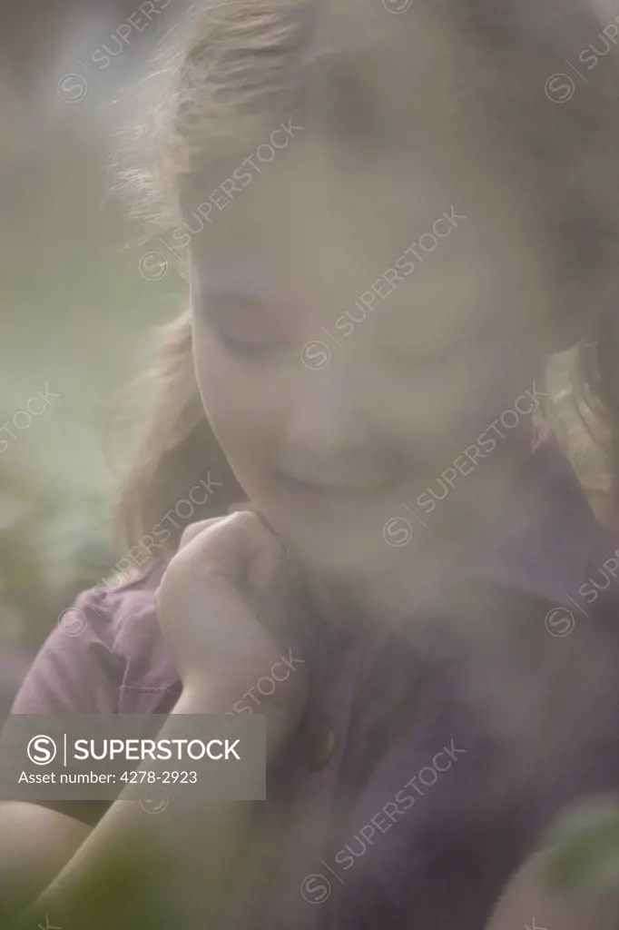 Close up of girl shot through glass from inside greenhouse