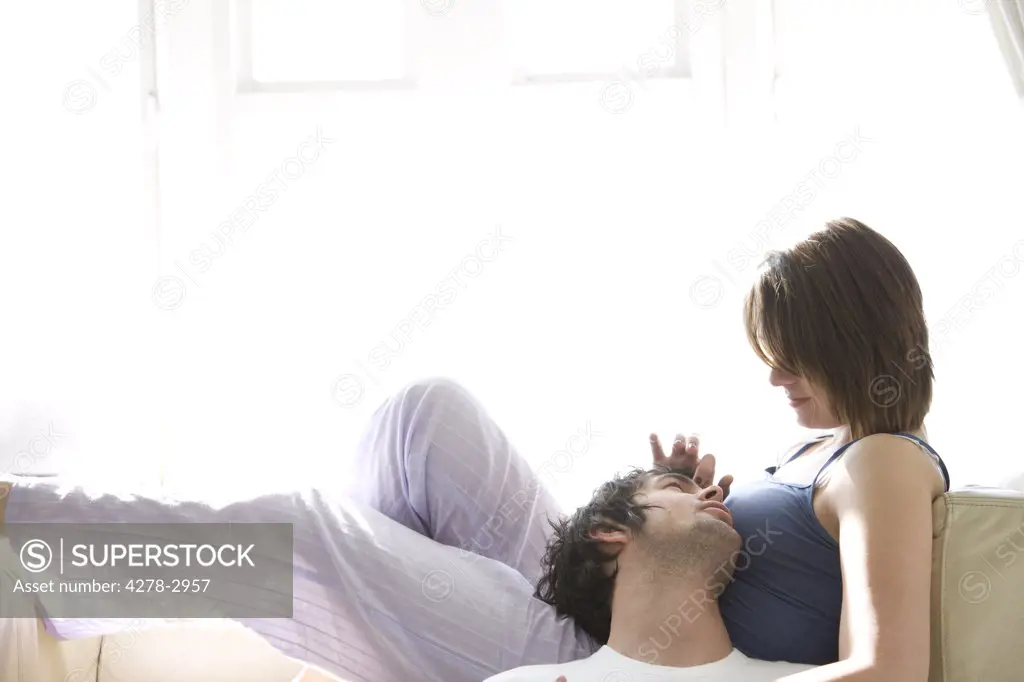 Couple talking and looking at each other with woman lying on sofa
