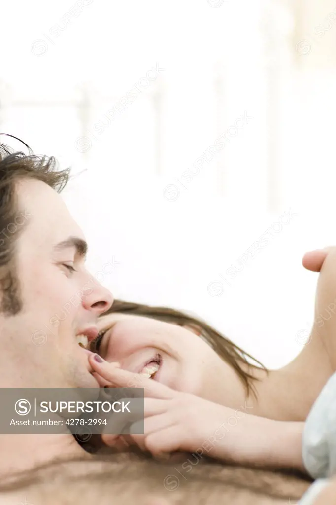 Close up of couple in bed laughing