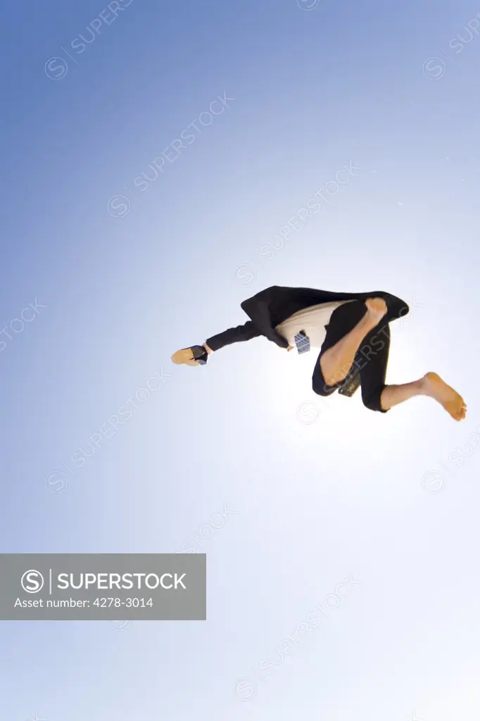 Businessman jumping mid air holding shoes