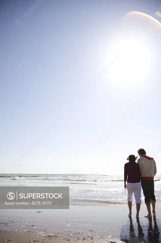 Back of young couple walking on a beach
