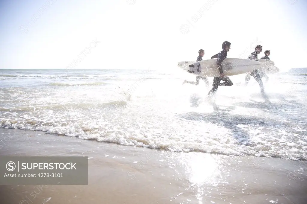 Surfers running in the sea holding surfboards