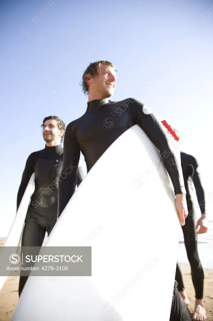 Surfers walking on the beach holding surfboards