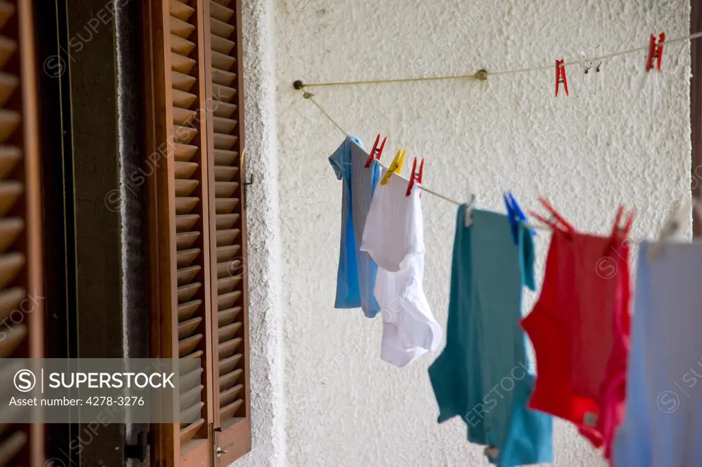 Clothes line with clothes and pegs next to a window with shutters