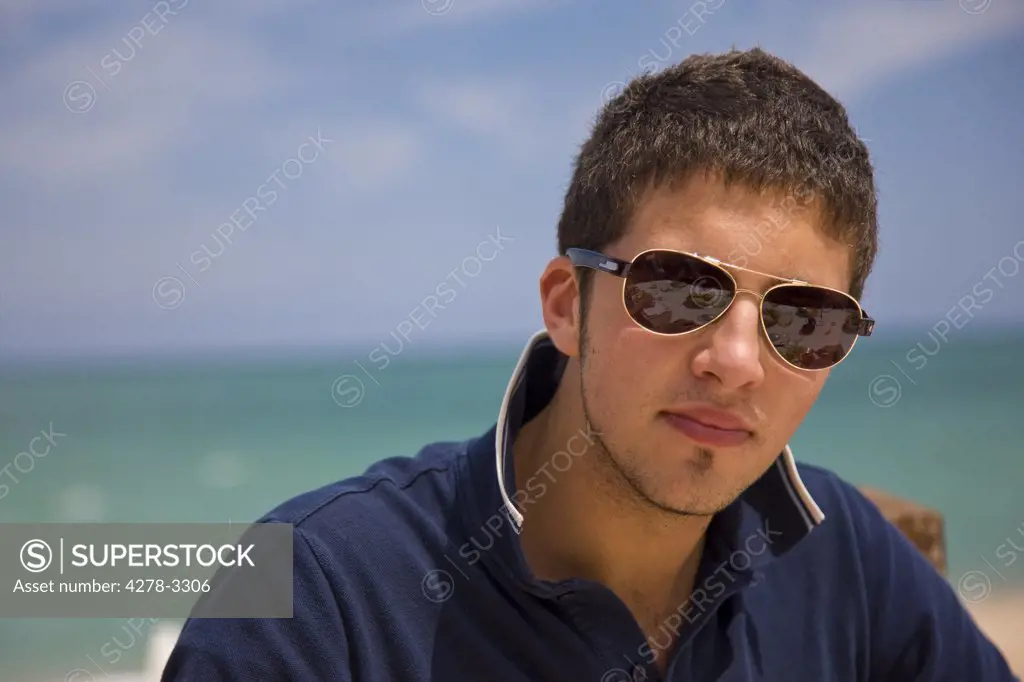 Close up of a young man with sunglasses by the sea