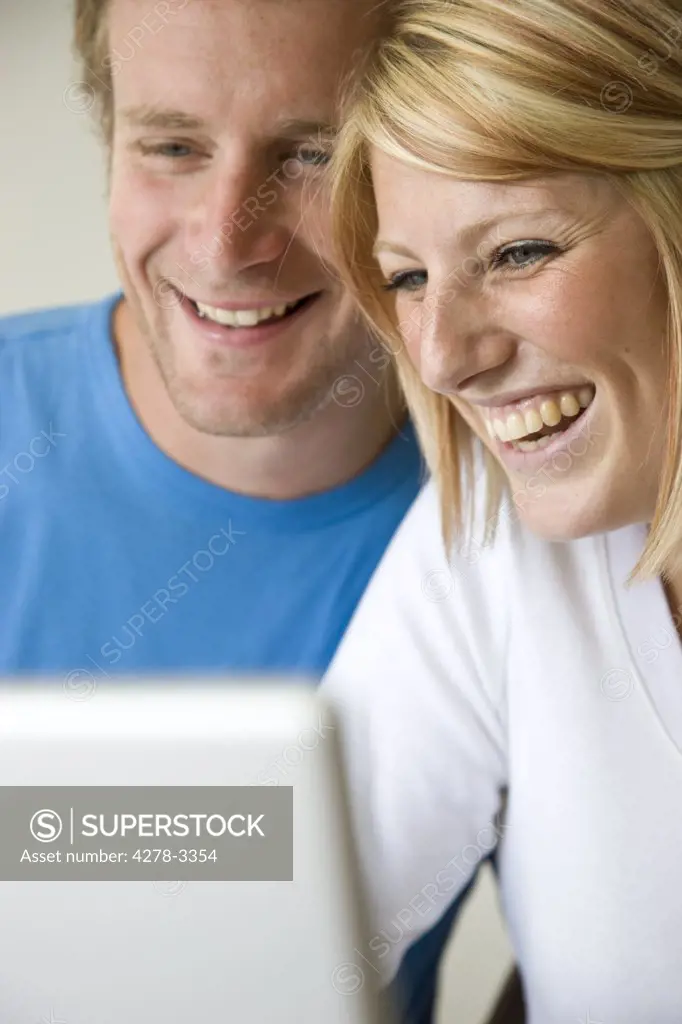 Close up of a couple laughing and looking at laptop computer screen