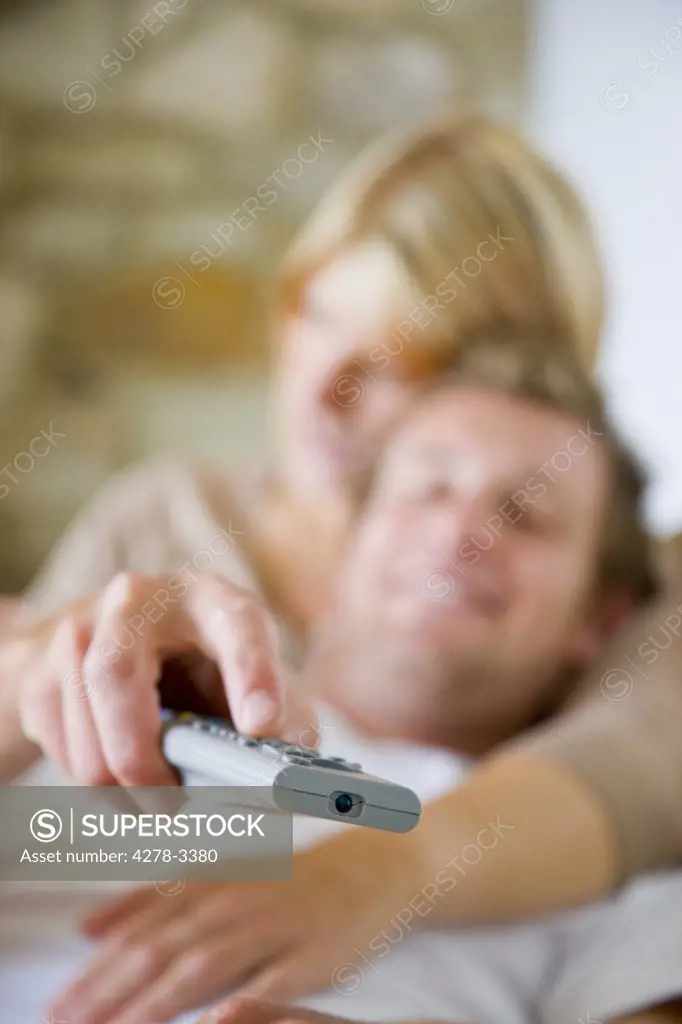Man leaning against woman shoulder with hand holding remote control