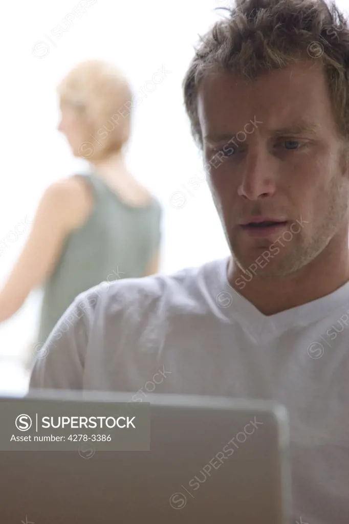 Man looking at laptop computer with woman standing behind him
