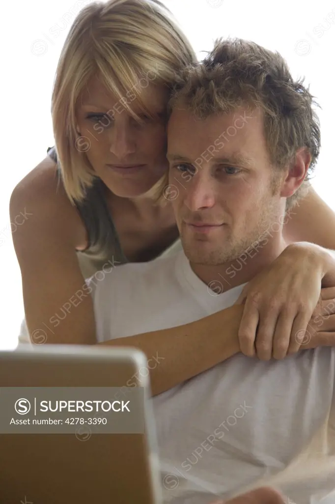 Young couple looking at laptop computer screen embracing