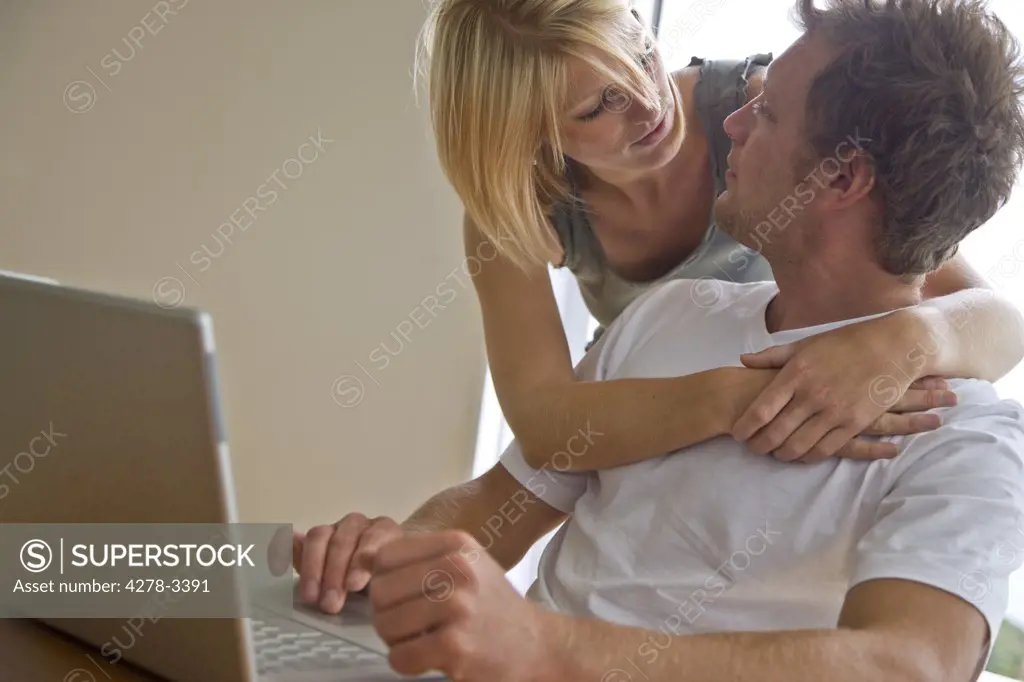 Couple sitting in front of laptop embracing