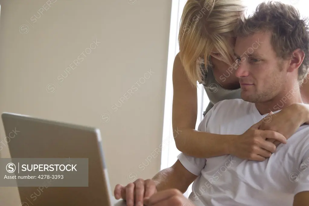 Young couple in front of laptop computer  embracing