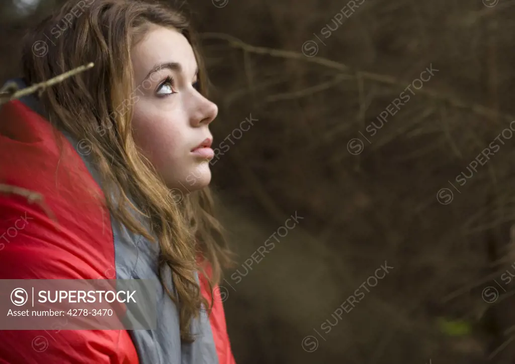 Teenaged girl wrapped in a sleeping bag at campsite