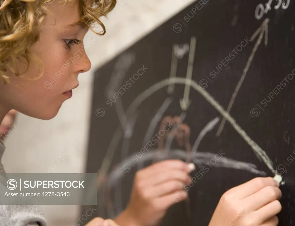 Young boy writing on a blackboard