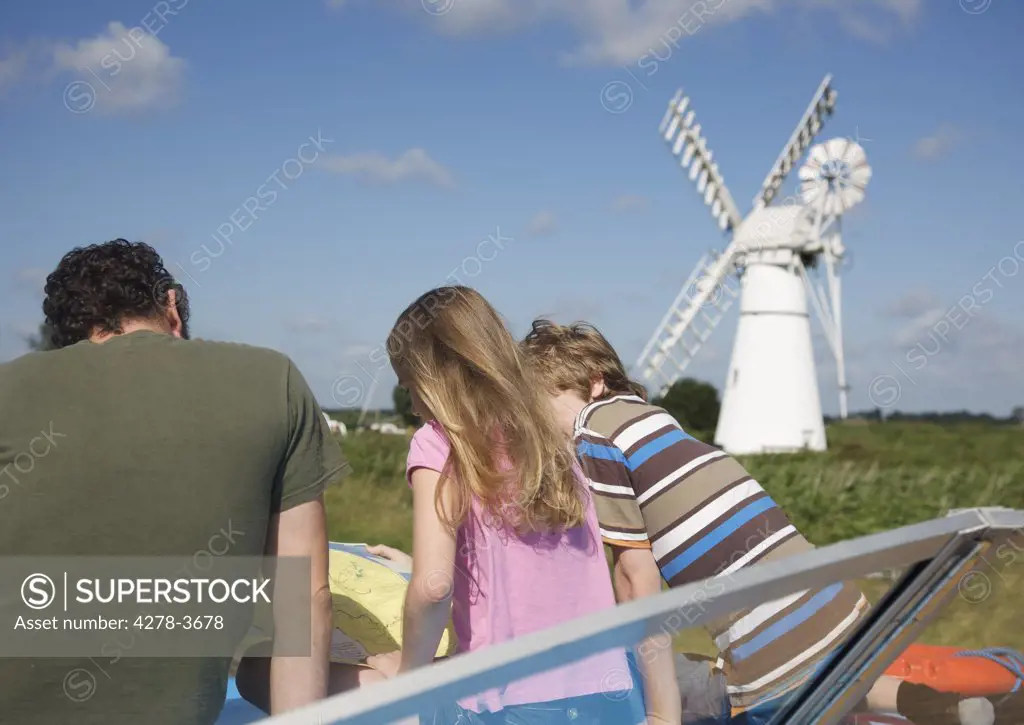 Back view of a man and children looking at a map