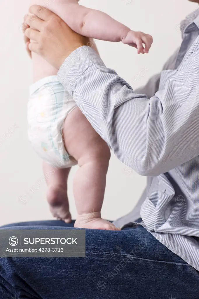 Man sitting with newborn baby standing on his lap