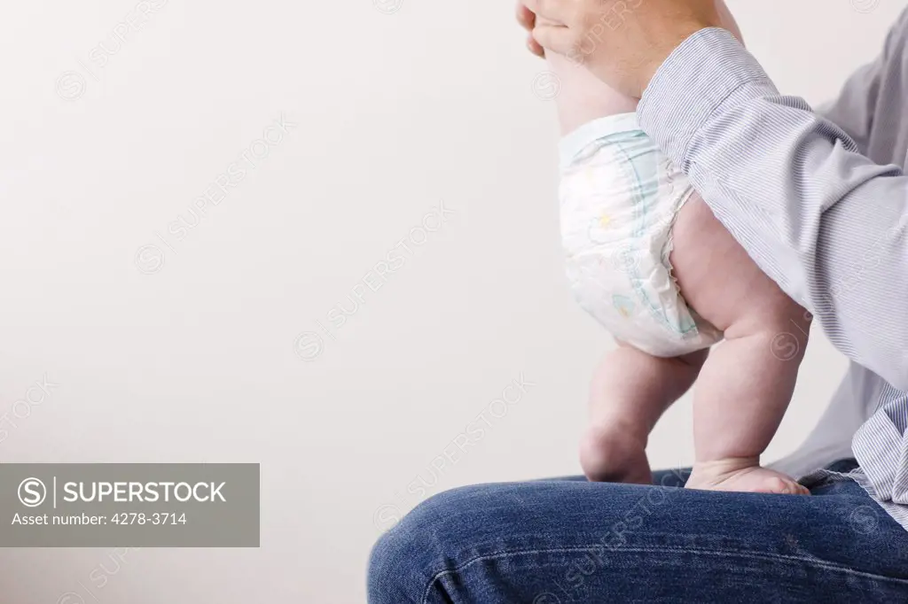 Man sitting with newborn baby standing on his lap