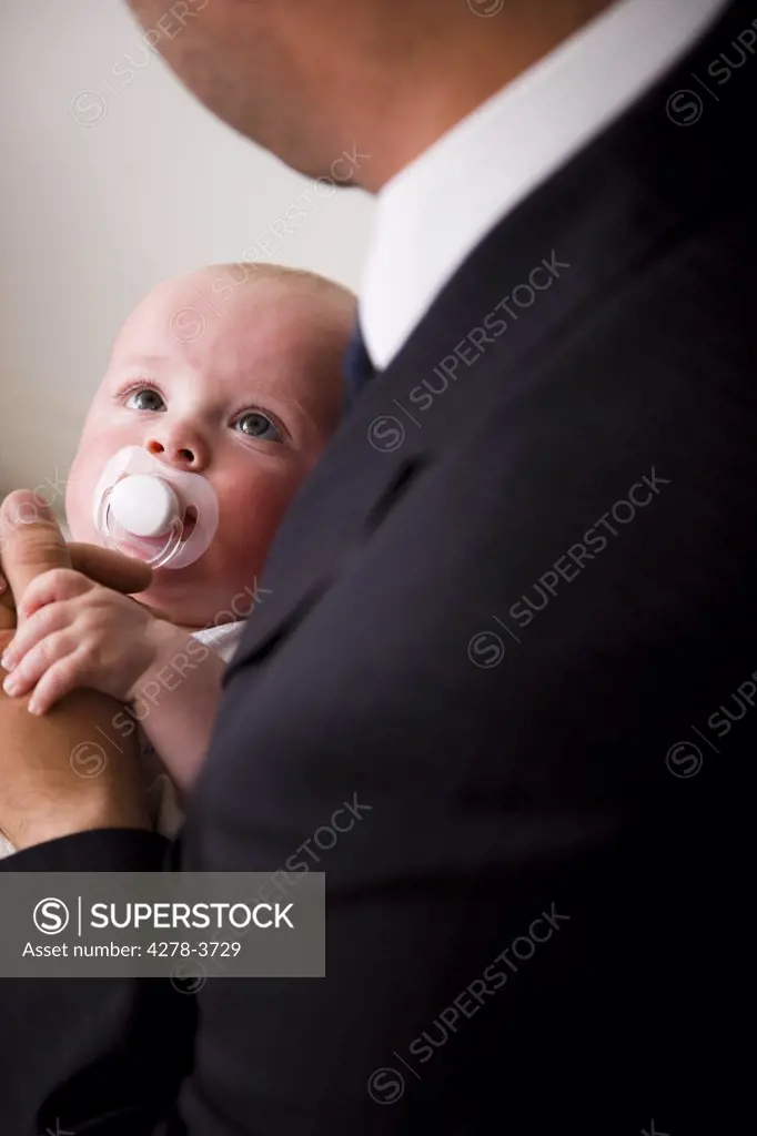 Back view of a businessman holding a baby
