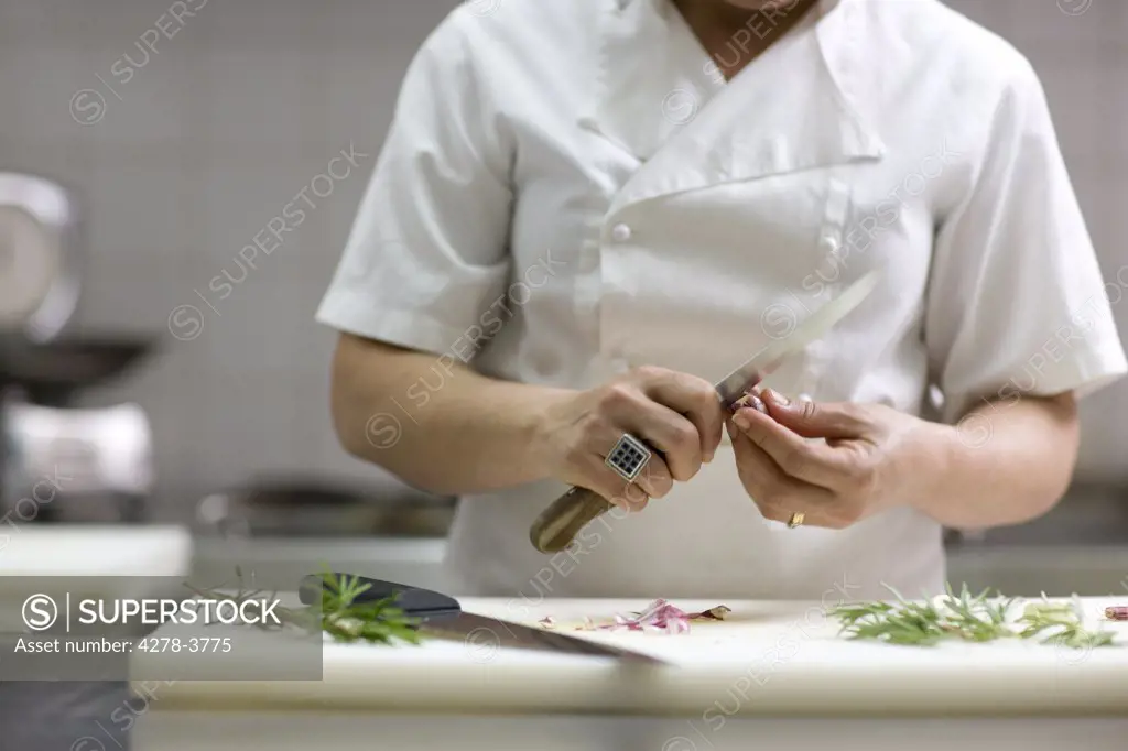 Close up of a chef peeling garlic with a knife