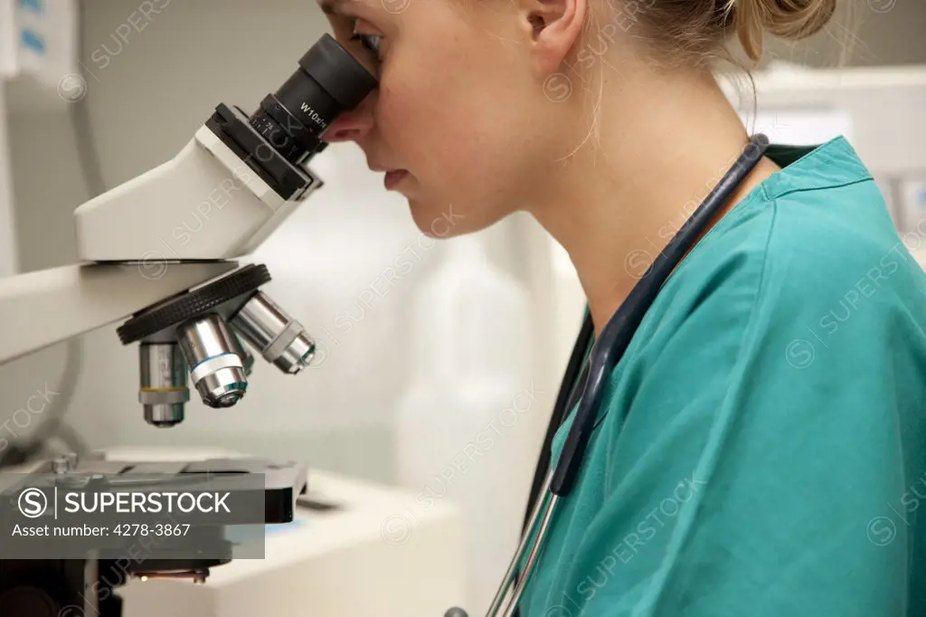 Lab technician looking into microscope