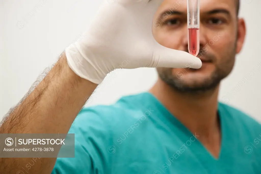 Healthcare professional holding a test tube between his fingers