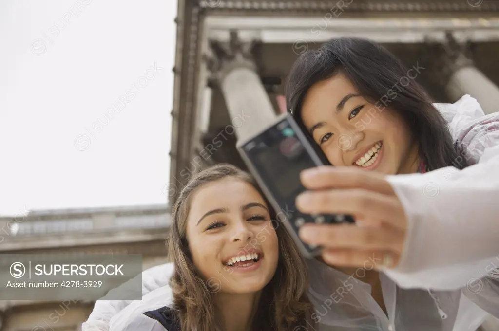 Two teenage girls taking self-portrait with cell phone in front of National Gallery