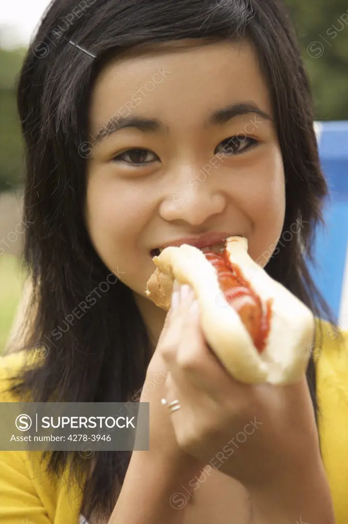 Close up of a teenaged girl eating a hot dog