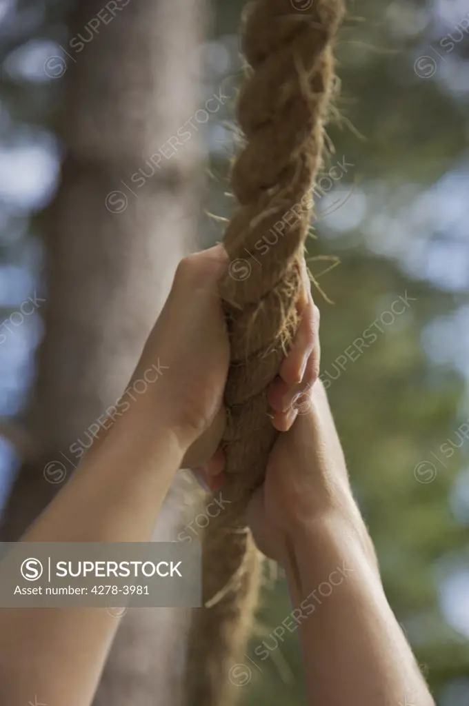 Close up of a woman hands hanging from a rope