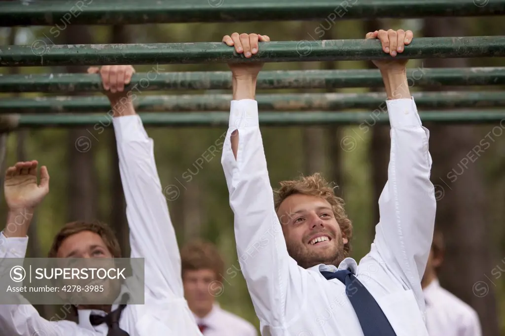 Two businessmen at an obstacle course dangling from parallel bars