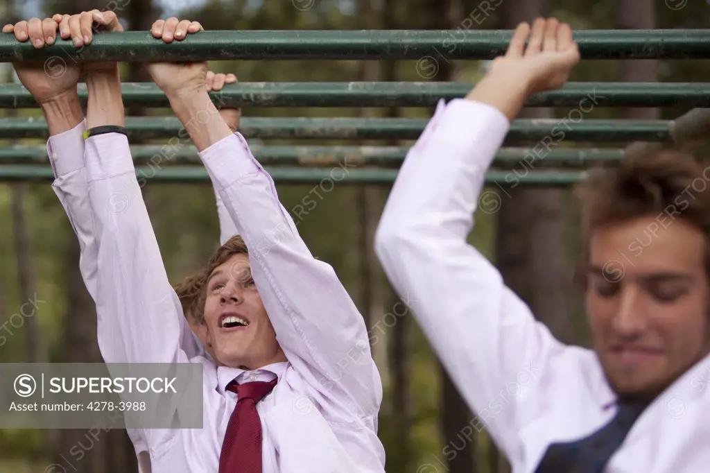 Businessmen at an obstacle course dangling from parallel bars