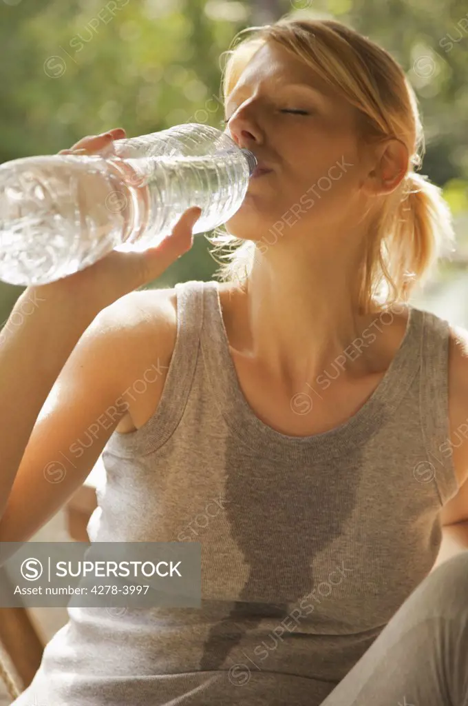 Close up of a young woman drinking water from a bottle with her eyes closed