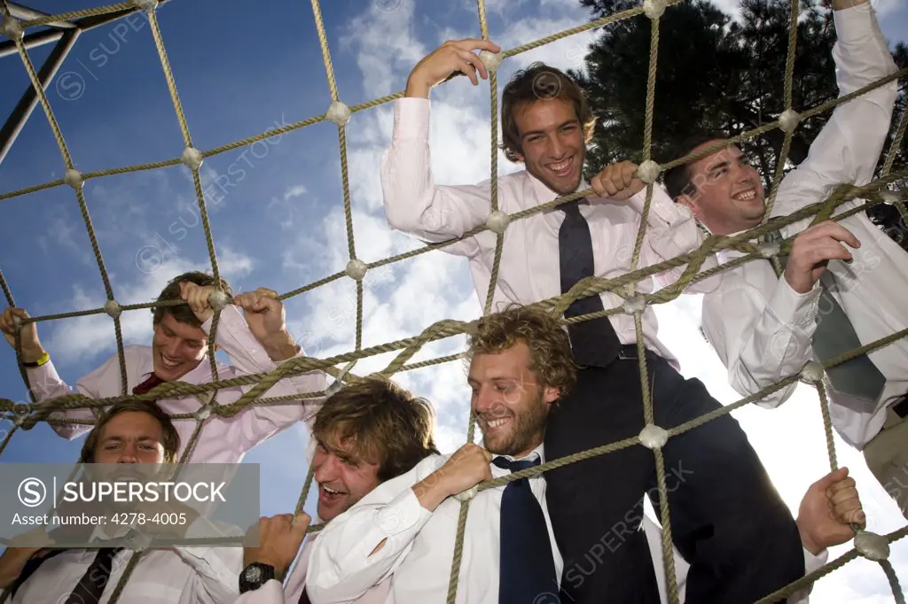 Businessmen at an obstacle course climbing a cargo net