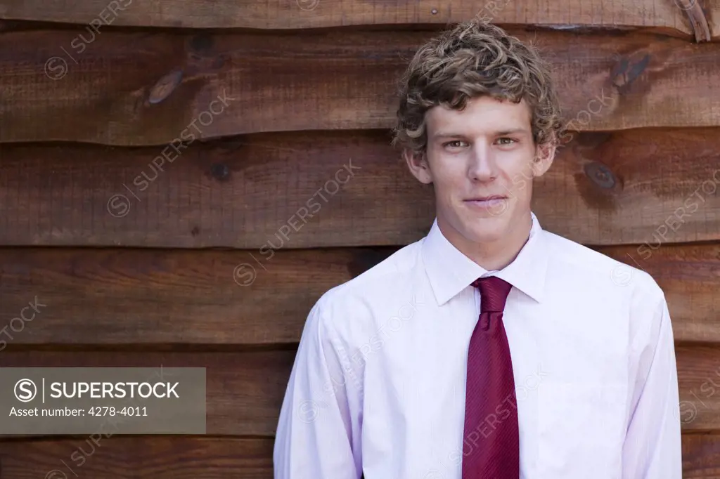 Young businessman standing against a wood wall