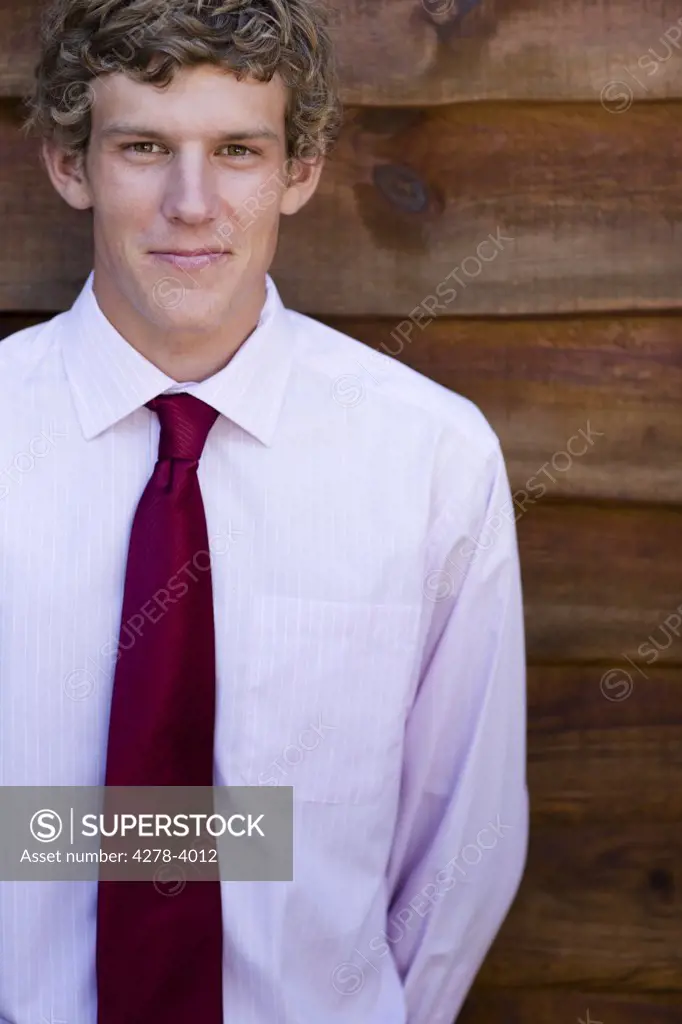 Young businessman standing against a wood wall