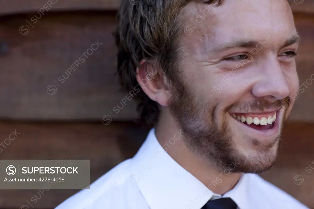 Businessman standing against a wood wall laughing