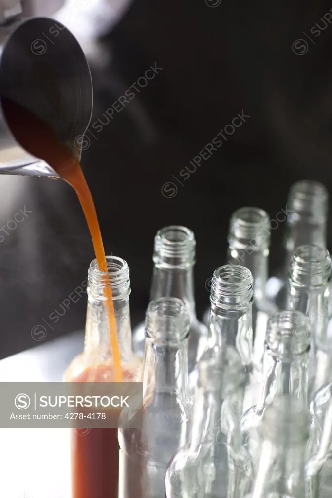 Tomato sauce being poured into a glass bottle