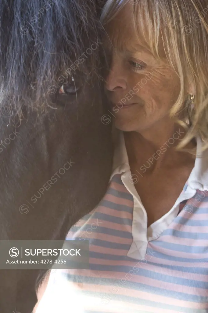 Close up of a mature woman standing next to horse head