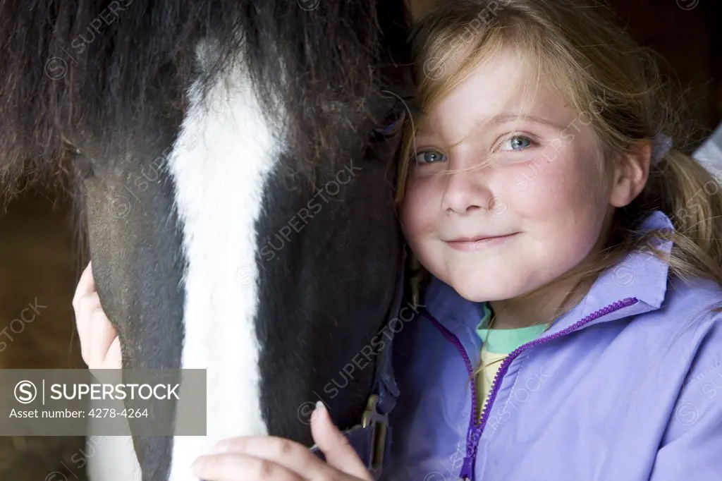 Young girl hugging a horse head