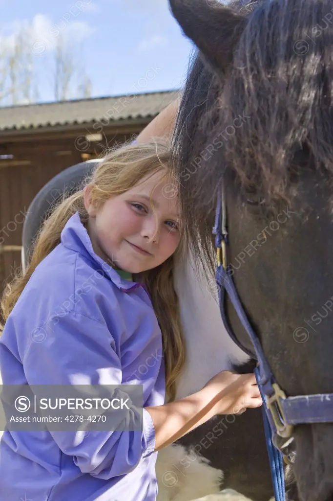 Smiling young girl hugging a horse