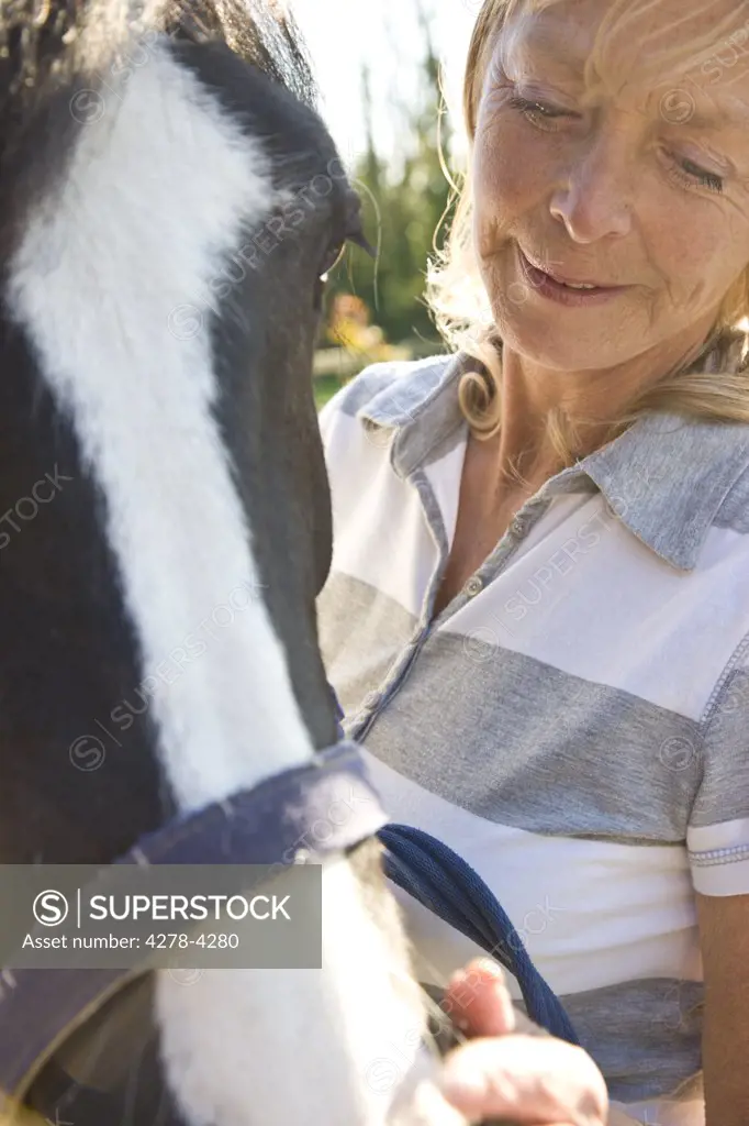 Mature woman standing next to a horse