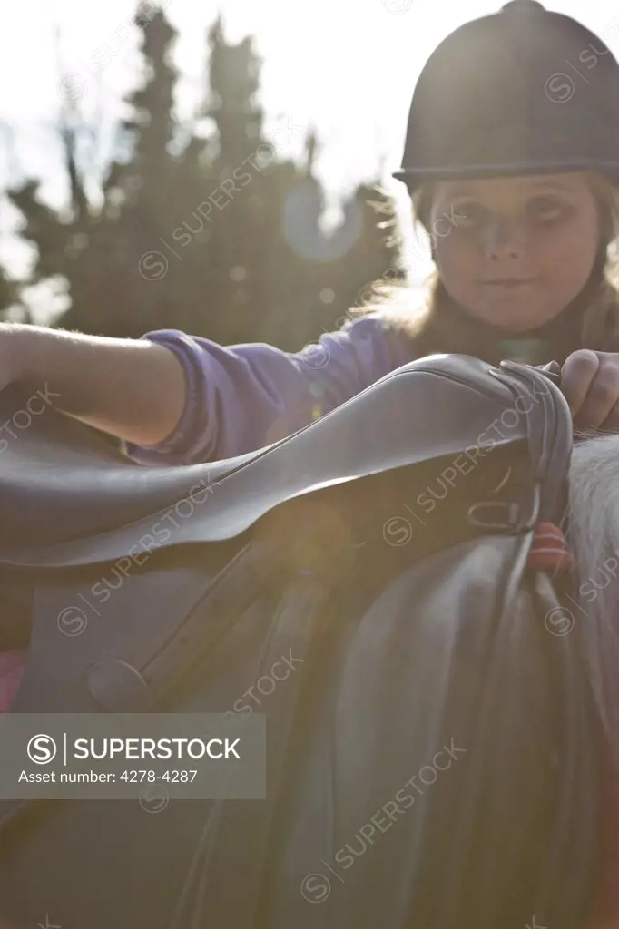 Young girl getting on a horse