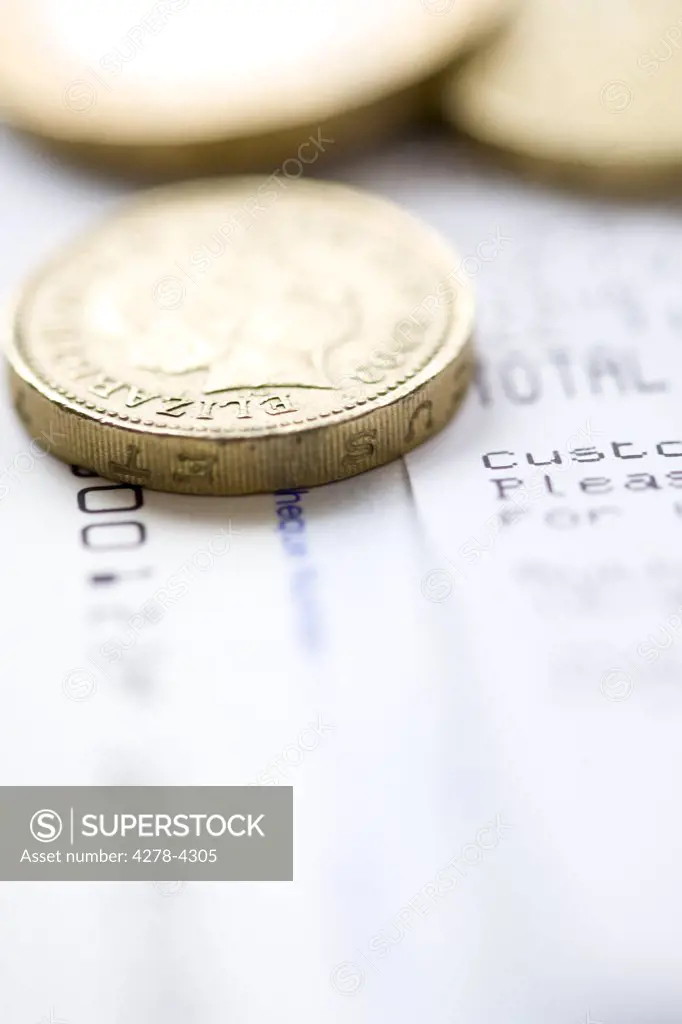 Close up of loose pound sterling coins on top of receipts
