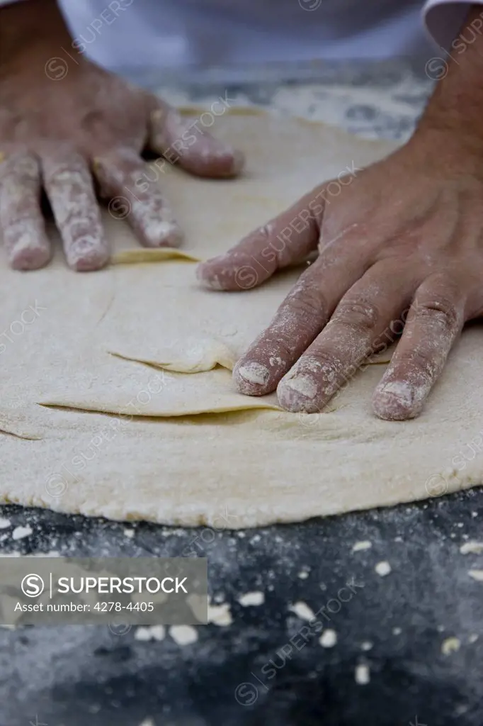 Close up of a chef hands covered in flour kneading a pizza dough