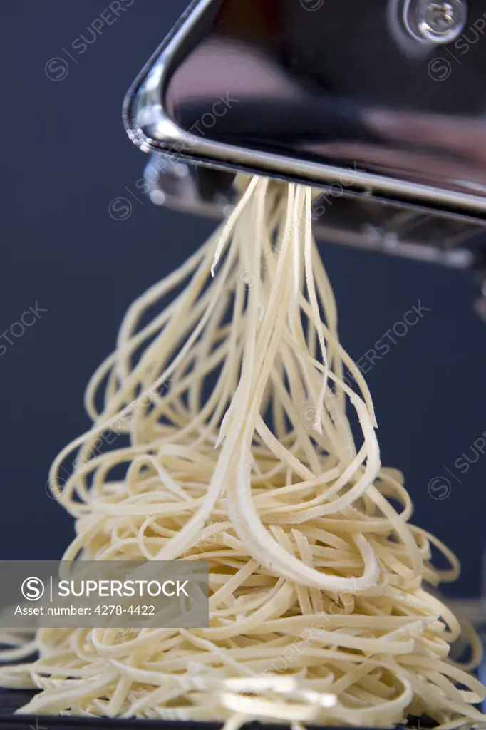 Heap of fresh tagliolini coming out of a pasta maker