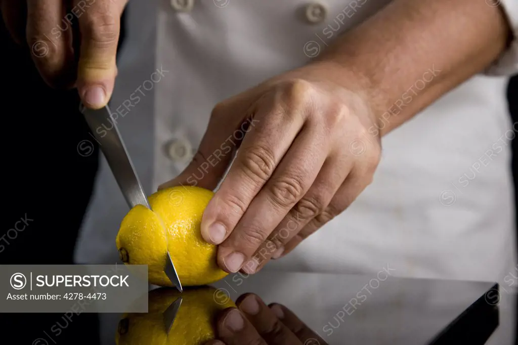 Close up of a chef hands slicing a lemon